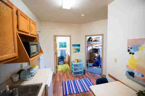 Interior hallway and kitchenette is shown with doorways to a bathroom and bedroom